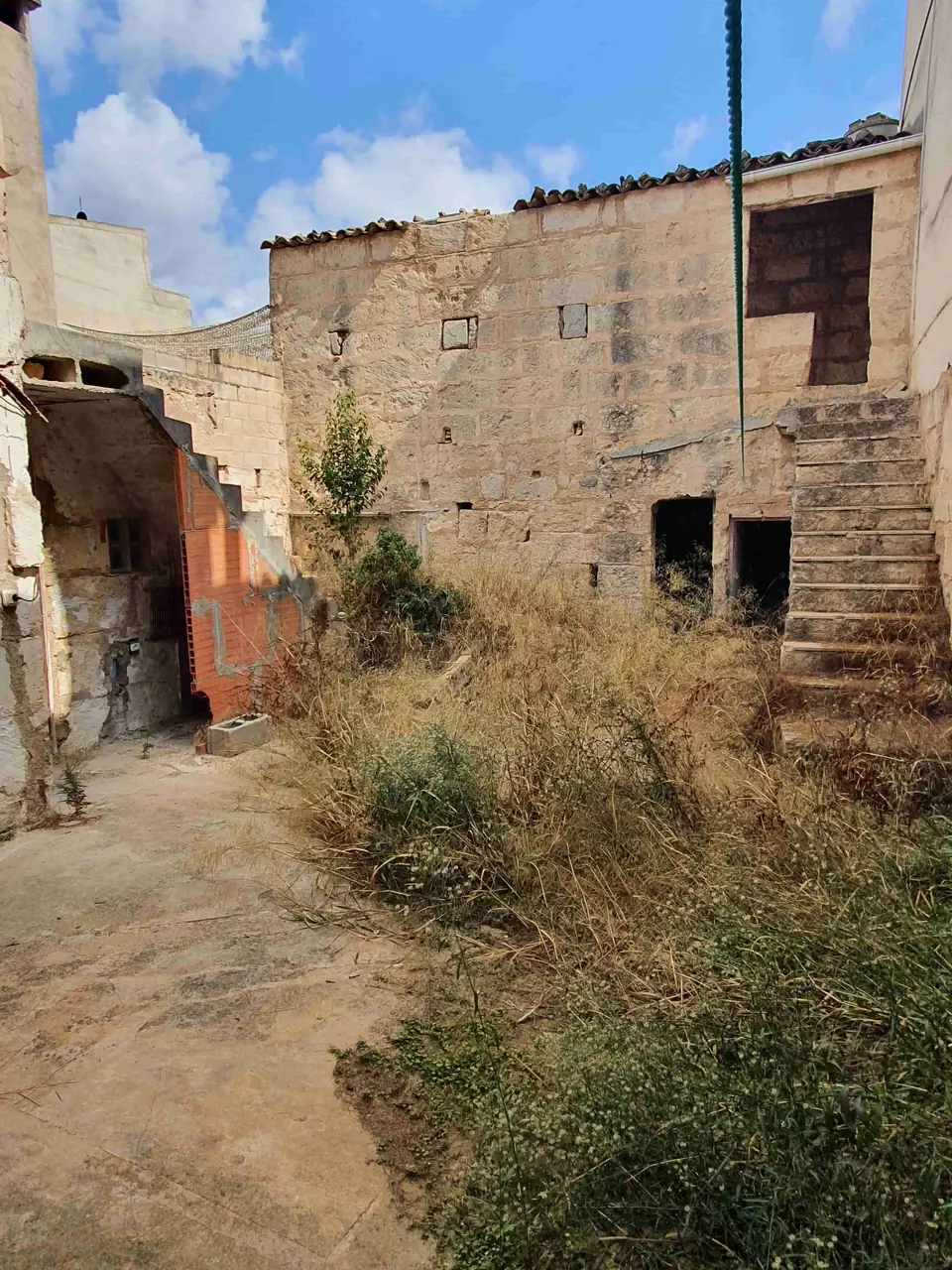 El patio en 2021, con maleza y muros sin restaurar